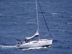 white yacht with the lowered sail on the water