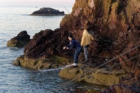 the boys are fishing near the cliff