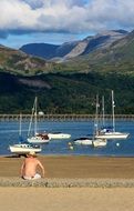 young man on the sunny beach on the background of yachts