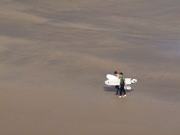 walking surfers on a beach in summer