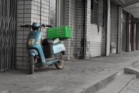 battery scooter with delivery basket at wall outdoor