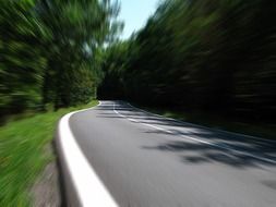 asphalt road through the green forest with blurry landscape