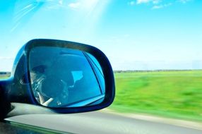 the reflection of the photographer in the side mirror of the car