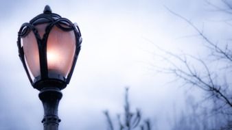 city lamp with light on the street at dusk