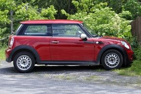 side view of red mini car at greenery