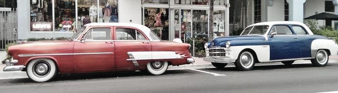 two oldtimer autos on street at shop display