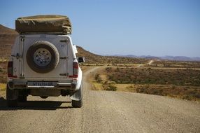 back view of loaded jeep on gravel road in desert, namibia