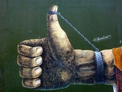 hand with chained thumb up, graffiti on wall