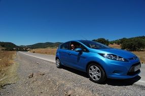 blue ford on the road on a sunny day