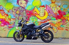 black streetbike at wall with colorful graffiti