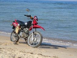 red motorcycle on the beach by the sea