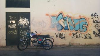 motorcycle stands near a wall with graffiti