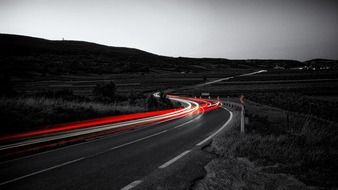 black and white photo of red lights on the night road