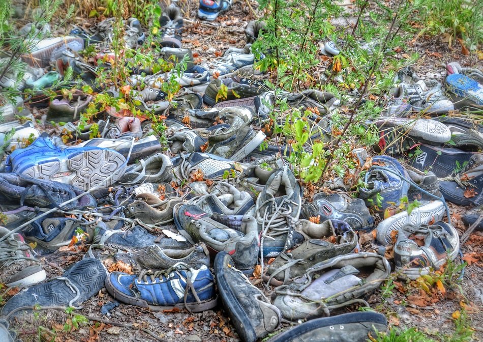 lot of old worn out shoes in a landfill