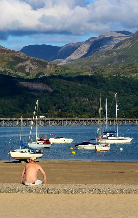 young man on the sunny beach on the background of yachts