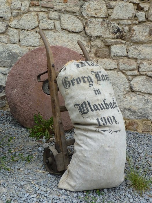 millstone, sack of flour, and a cart in open air museum