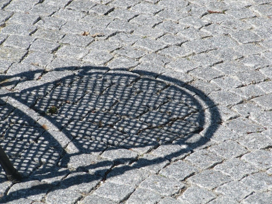 shadow from wicker chair on the pavement