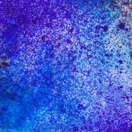 Paint splatter in bright blue and purple colors on paper