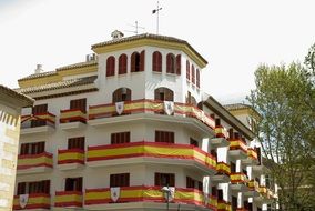 flags on the balconies of a white building in Andalusia