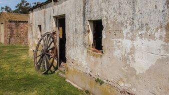 Facade of a ruined building with empty windows and a wheel