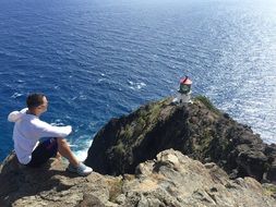 man sits on a rock by the sea