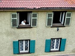 person in the window with shutters