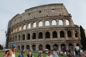 people on a green lawn in front of the coliseum