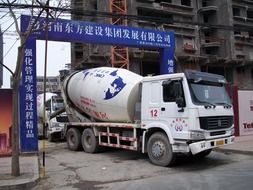 truck with concrete mixer in gateway of construction site