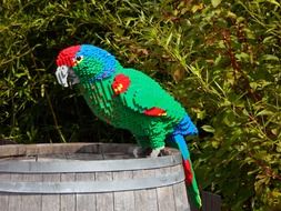 A parrot on a barrel made of colorful Lego blocks