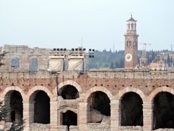 View of the arena in Verona on the background of the bell tower near the trees