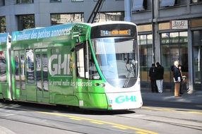 green modern tram on a city street