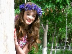 photo of a girl in a wreath of blue flowers in the park