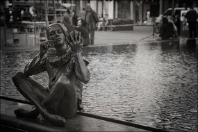 Metal sculpture of siting human on the fountain