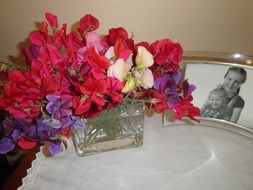bouquet of bright flowers and photo of two child girls on table
