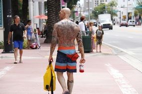 a man with tattoos on his body is walking down the street