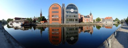 buildings are reflected in the water on the embankment in bydgoszcz