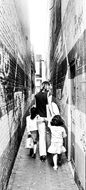 black and white photo of people on a narrow alley