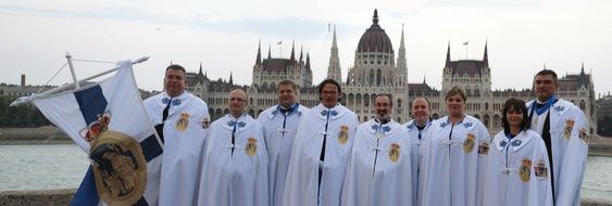 people in medieval costumes in front of parliament building, hungary, budapest