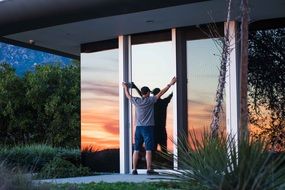 young man stands by the glass door on the terrace