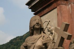 statue of a girl with her eyes closed and the cross of the heidelberg bridge