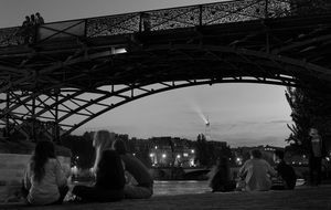 people on the river bank under the bridge in paris
