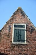 window closed with wooden shutter on brick facade