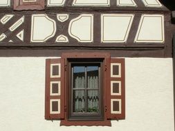 window with brown shutters on wall of old timber framed house