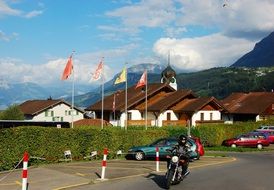 man riding motorcycle on road in front of village church, switzerland, lucerne region