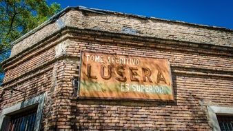 Facade of an old brick building with the inscription "lusera"