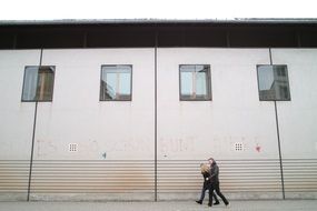 couple walking on pavement along modern building