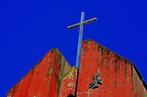 cross on a wooden church under a blue sky