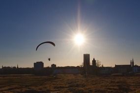 paraglider over city at sunset