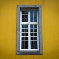 grated window in yellow facade