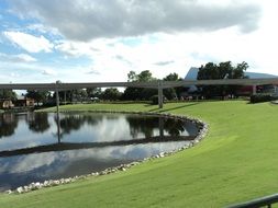 bridge over a lake in a park with green hills